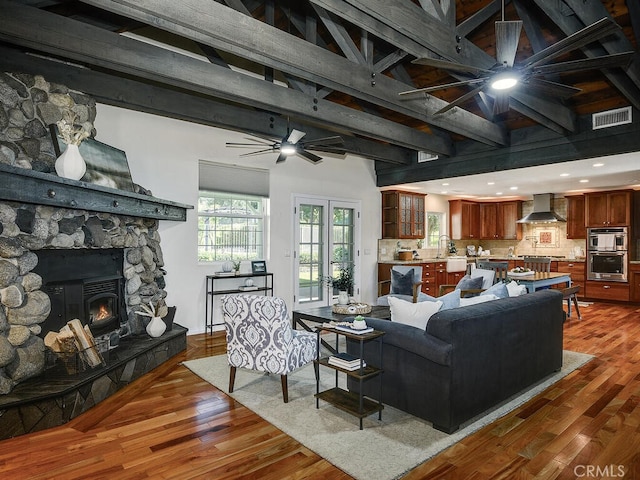 living area with wood-type flooring, beam ceiling, ceiling fan, and visible vents