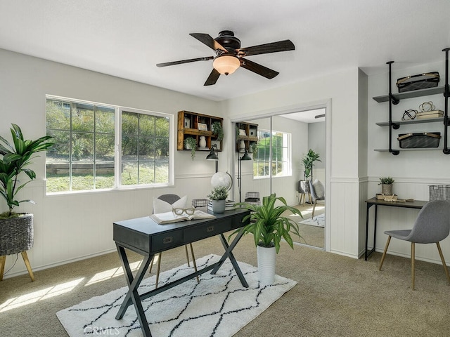 carpeted home office with wainscoting and ceiling fan