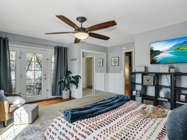 bedroom with wainscoting, wood finished floors, ceiling fan, and access to outside