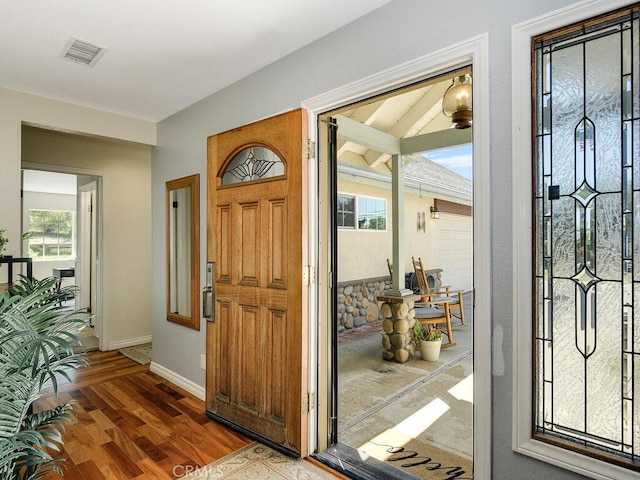 foyer featuring baseboards, visible vents, and wood finished floors
