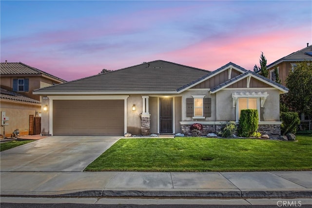 craftsman-style house featuring stucco siding, an attached garage, concrete driveway, and a front lawn