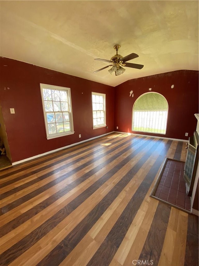 unfurnished room with a ceiling fan, vaulted ceiling, wood finished floors, and baseboards