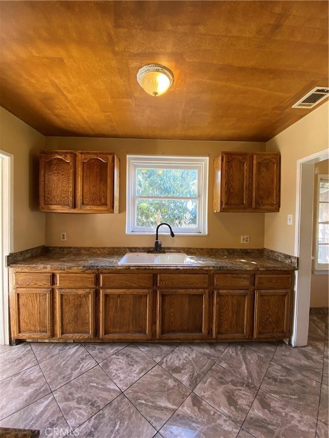 kitchen with dark countertops, visible vents, wood ceiling, and a sink