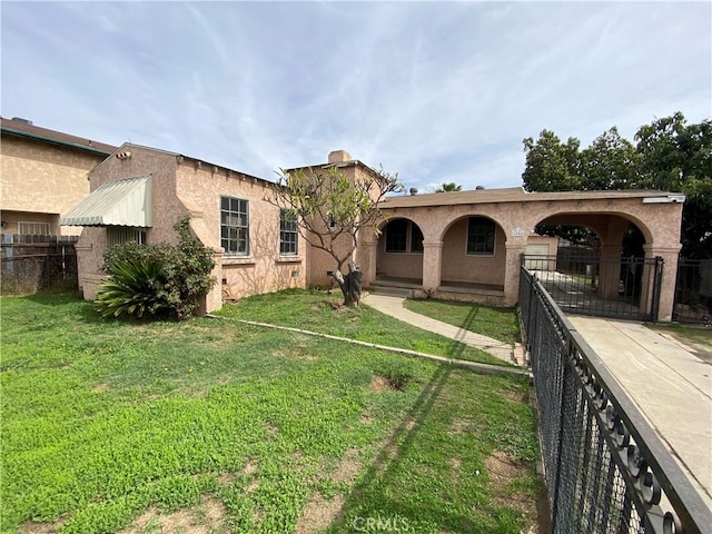 view of front of property featuring stucco siding, a front lawn, and fence