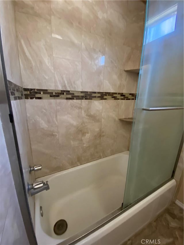 bathroom with bath / shower combo with glass door