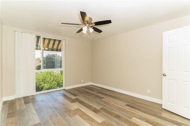 spare room featuring wood finished floors, baseboards, and ceiling fan