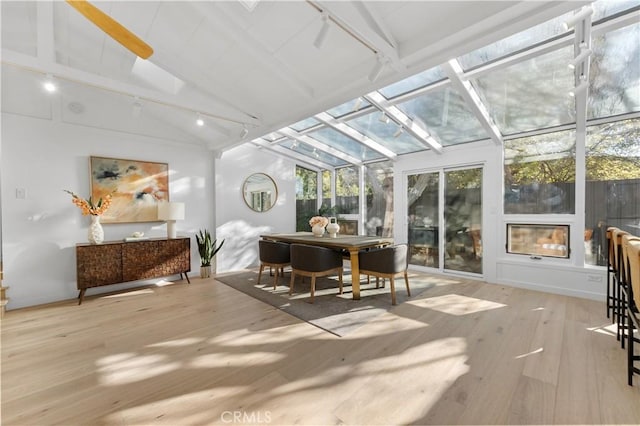 sunroom with rail lighting, a fireplace, and vaulted ceiling with beams