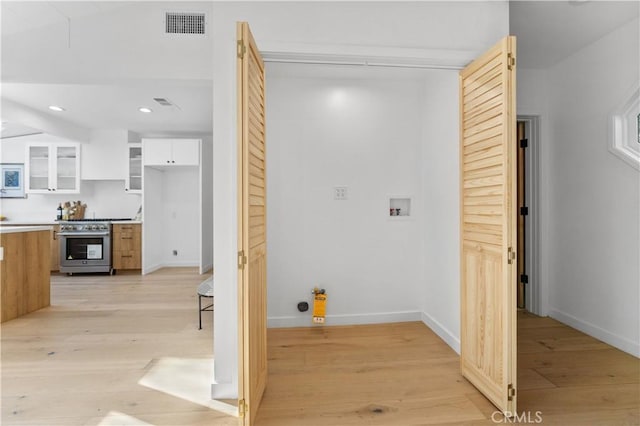 clothes washing area featuring hookup for a washing machine, baseboards, laundry area, recessed lighting, and light wood-style floors