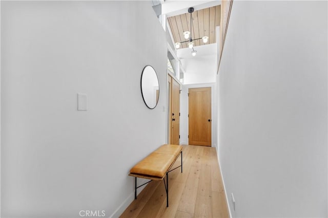 hall with a high ceiling, light wood-style floors, and baseboards