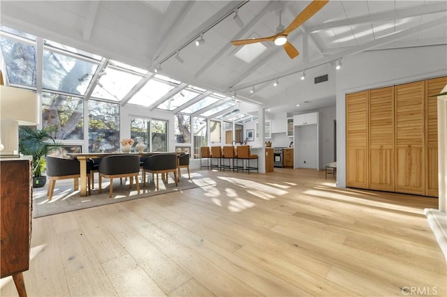 sunroom / solarium featuring lofted ceiling with beams, rail lighting, visible vents, and ceiling fan