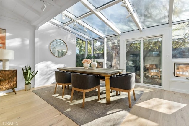 sunroom / solarium with a healthy amount of sunlight, rail lighting, and vaulted ceiling with beams