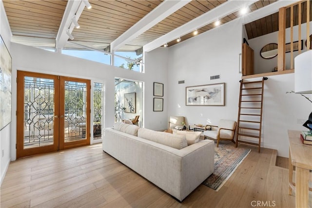 living room featuring beam ceiling, track lighting, stairway, wood-type flooring, and french doors