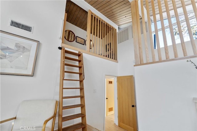 stairs featuring a high ceiling, wood finished floors, and visible vents