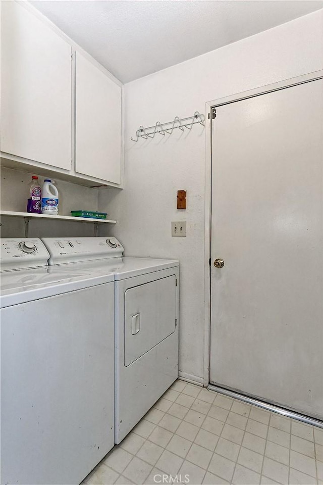 clothes washing area featuring cabinet space and washer and clothes dryer