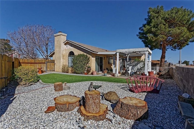 back of property featuring stucco siding, a chimney, a yard, a fenced backyard, and a patio