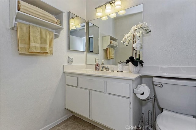 bathroom with baseboards, toilet, vanity, and tile patterned flooring