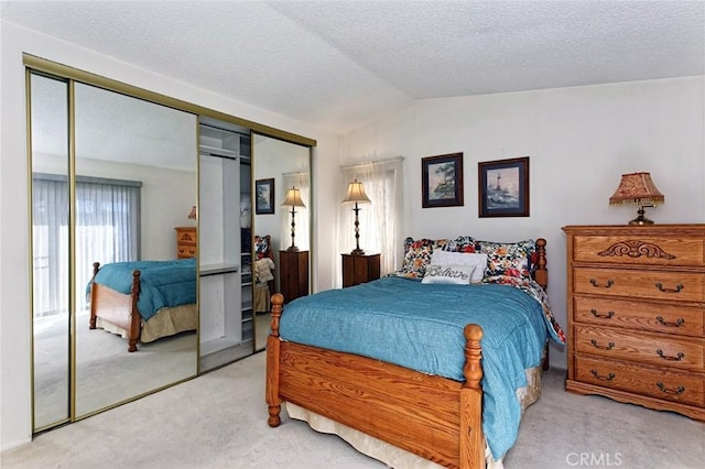 carpeted bedroom with vaulted ceiling, a closet, and a textured ceiling