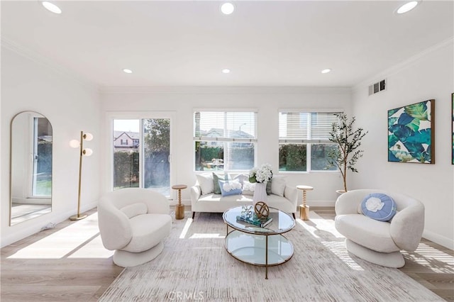 living area featuring visible vents, wood finished floors, and ornamental molding