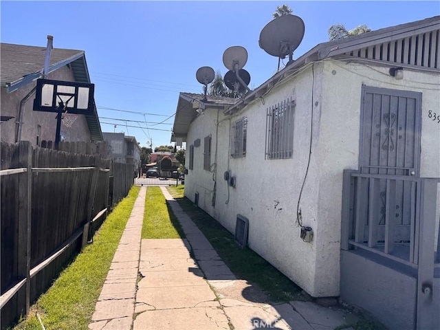 view of side of home with stucco siding and fence