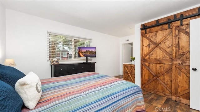 bedroom featuring a barn door and wood finished floors