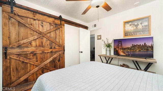 bedroom with a barn door, visible vents, and ceiling fan