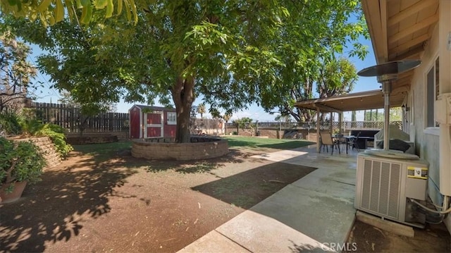 view of yard with an outdoor structure, central AC unit, a fenced backyard, and a shed