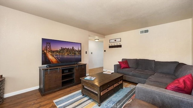 living room with wood finished floors, visible vents, and baseboards