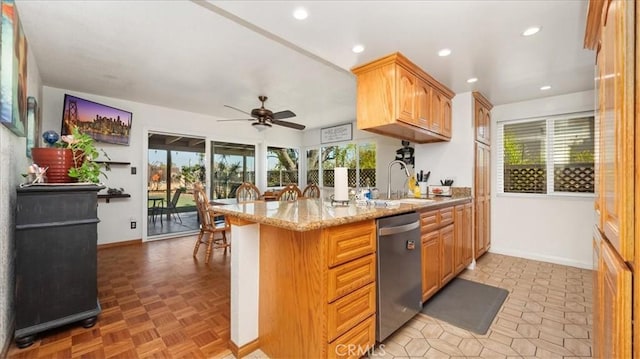 kitchen with light stone counters, stainless steel dishwasher, a healthy amount of sunlight, and a sink