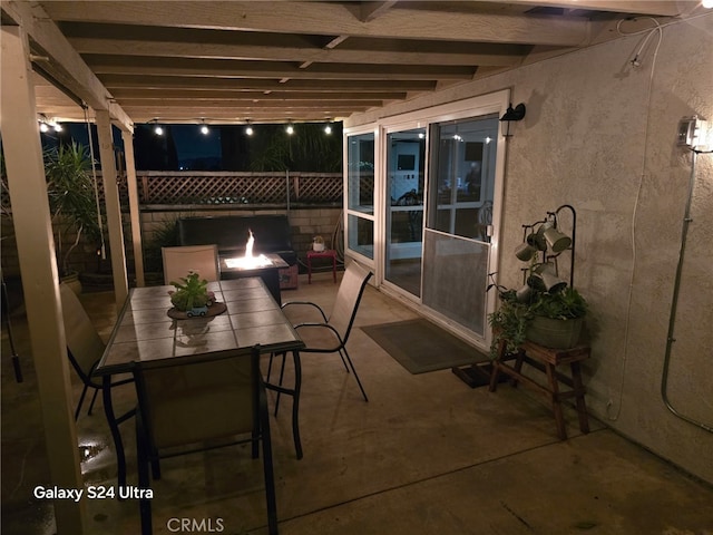 patio at twilight featuring outdoor dining area, fence, a grill, and an outdoor fire pit