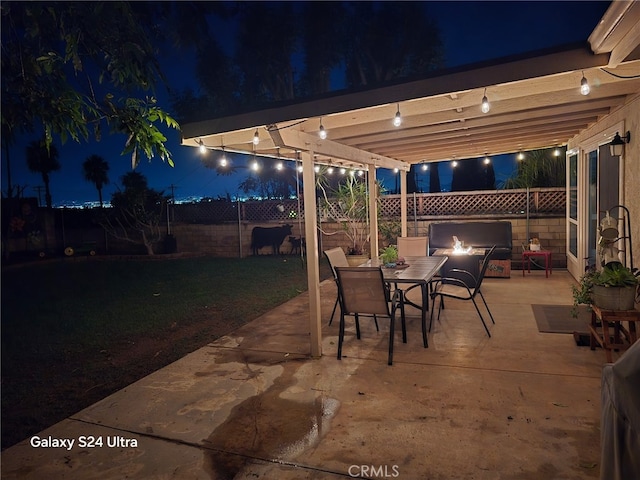 patio at twilight featuring a lawn, outdoor dining area, and a fenced backyard