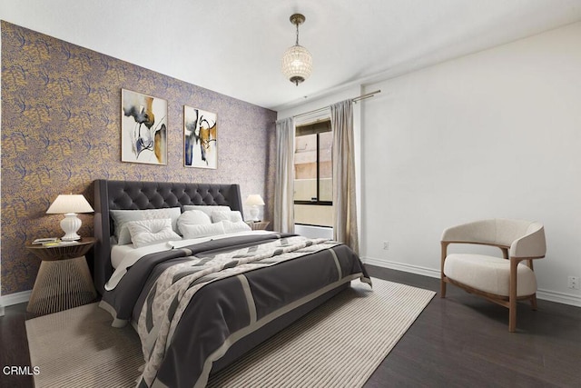 bedroom featuring baseboards, wood finished floors, and wallpapered walls