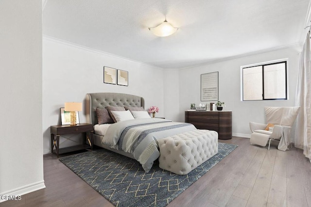 bedroom with wood finished floors, baseboards, and ornamental molding