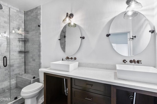 bathroom featuring double vanity, toilet, a stall shower, and a sink