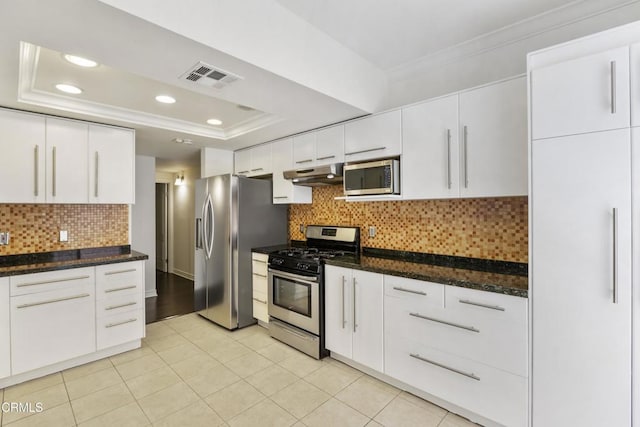 kitchen with visible vents, ornamental molding, under cabinet range hood, a tray ceiling, and appliances with stainless steel finishes