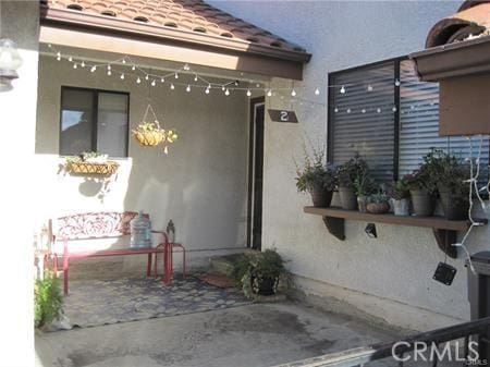 view of side of home with a tile roof, a patio area, and stucco siding