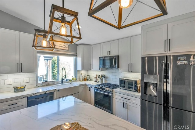 kitchen with a sink, appliances with stainless steel finishes, a toaster, decorative backsplash, and light stone countertops