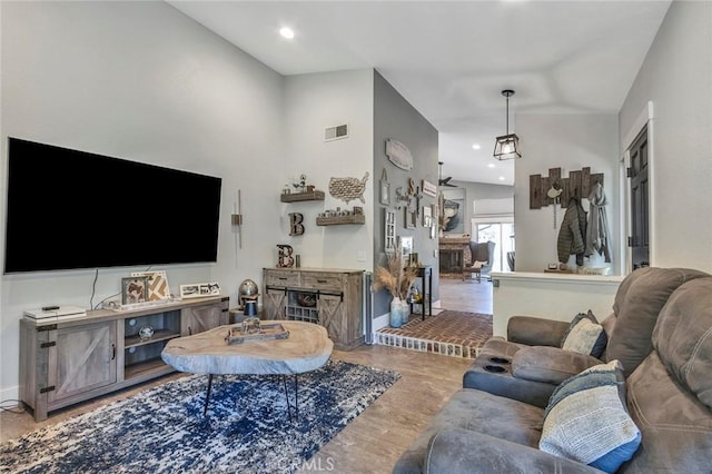 living room featuring visible vents, a brick fireplace, baseboards, recessed lighting, and wood finished floors