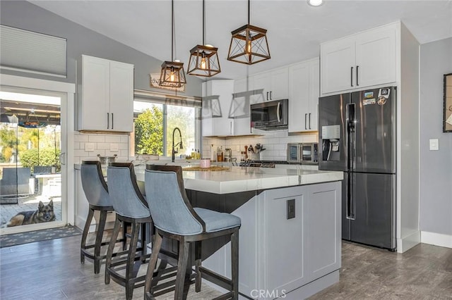 kitchen with dark wood-type flooring, white cabinetry, stainless steel appliances, decorative backsplash, and vaulted ceiling