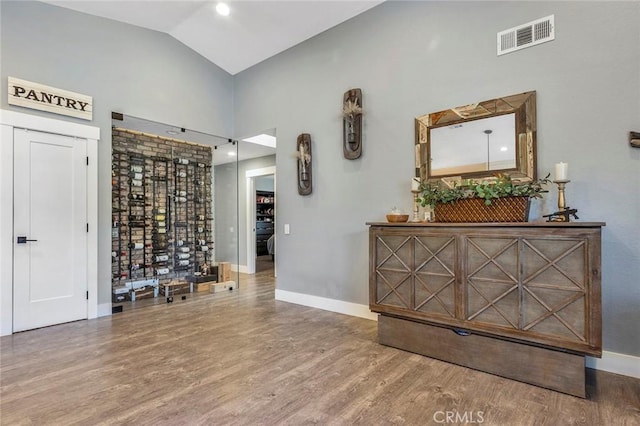 interior space with visible vents, baseboards, lofted ceiling, and wood finished floors