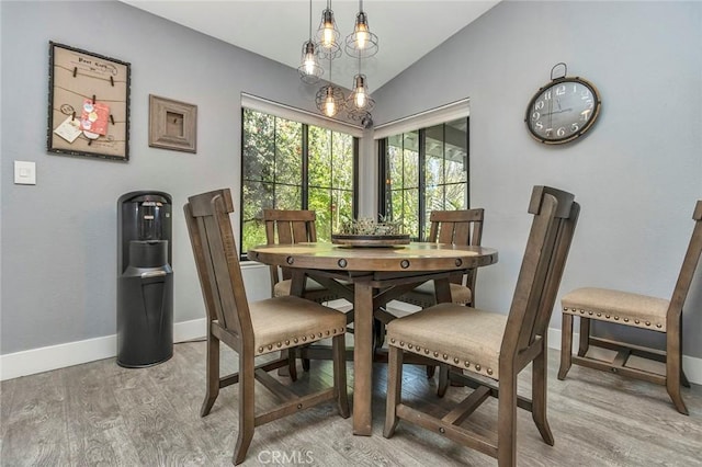 dining space with light wood-style flooring, baseboards, and vaulted ceiling