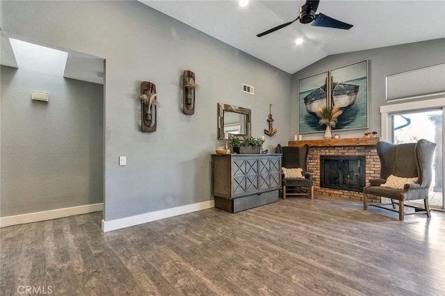 living area featuring visible vents, wood finished floors, baseboards, a fireplace, and lofted ceiling