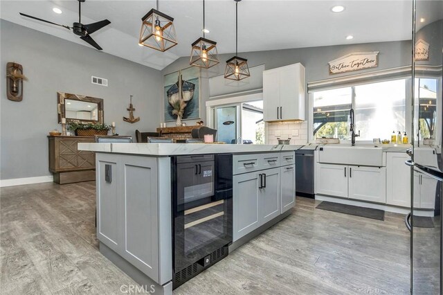 kitchen featuring beverage cooler, visible vents, a kitchen island, a sink, and stainless steel dishwasher