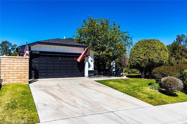 view of side of property with a lawn, board and batten siding, driveway, and a shingled roof