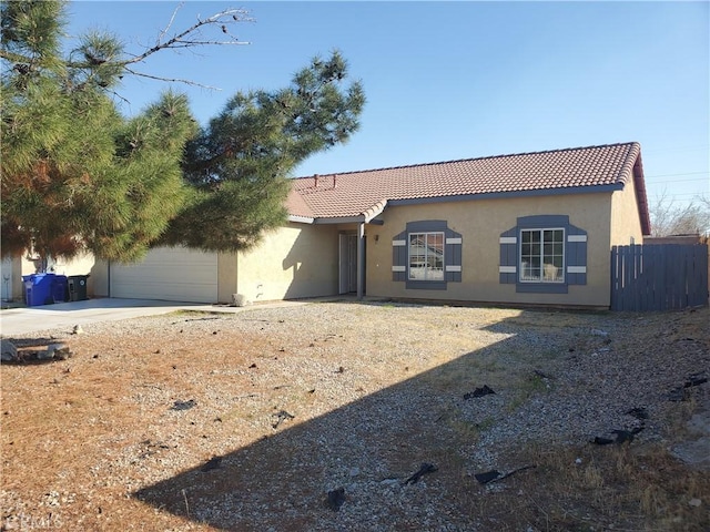 view of front of home with fence, driveway, an attached garage, stucco siding, and a tile roof