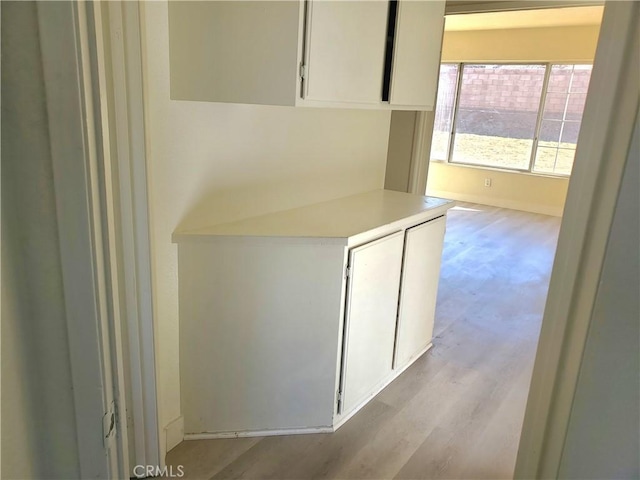 kitchen featuring light wood-type flooring, white cabinets, and light countertops