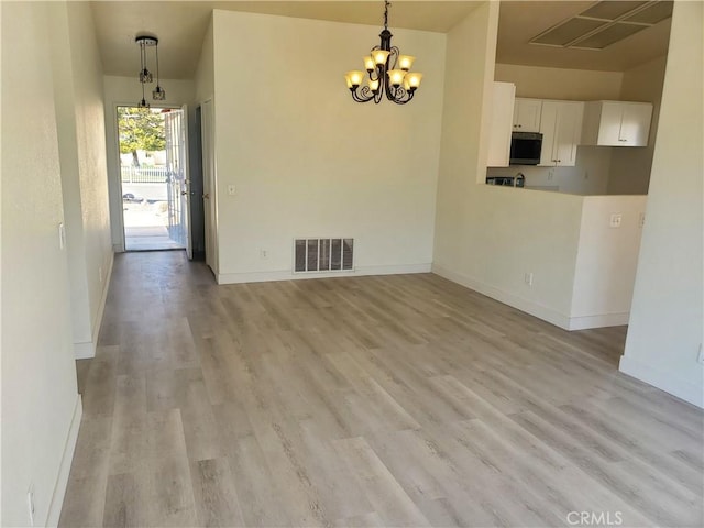 unfurnished dining area with visible vents, an inviting chandelier, light wood-type flooring, and baseboards