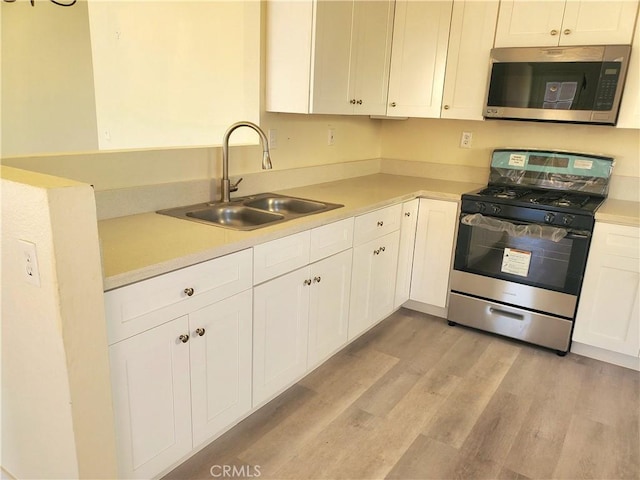 kitchen with light wood-type flooring, light countertops, white cabinets, stainless steel appliances, and a sink