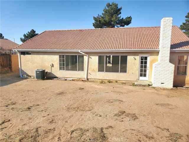 back of house featuring stucco siding, central AC, and a tiled roof