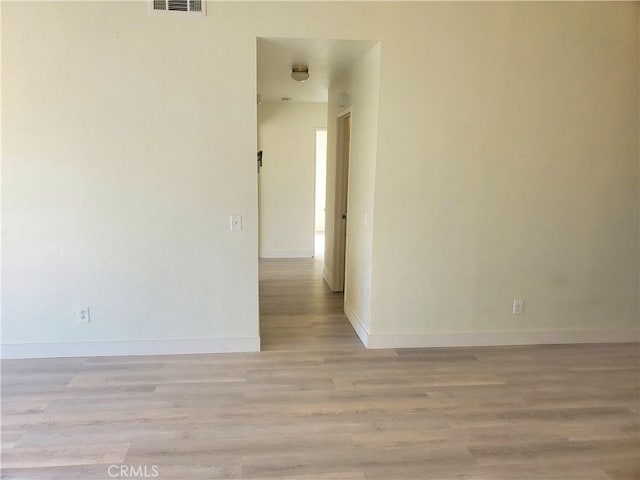 spare room featuring visible vents, light wood-style flooring, and baseboards