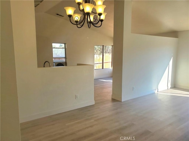 unfurnished room featuring baseboards, a notable chandelier, wood finished floors, and vaulted ceiling